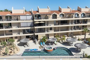 A multi-story hotel with a rooftop pool, lounge areas, and a desert garden. - Charming Golf-view Condo With Pool, Hot Tub, Terrace & Wifi (San José del Cabo)