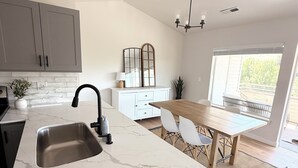 Eine moderne Küche mit Marmorarbeitsplatte, Spüle und einem Essbereich mit Tisch und Stühlen.