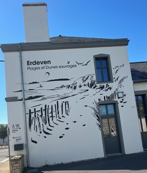 Un edificio con un mural que representa una playa y el texto 'Erdéven Plages et Dunes sauvages'.