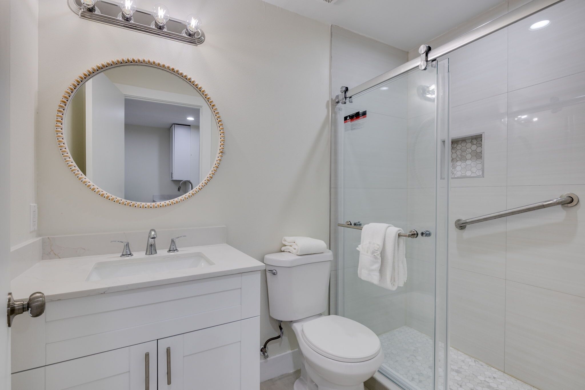 Une salle de bain équipée d’un lavabo, d’un miroir, de toilettes et d’une douche à parois en verre.