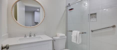 Une salle de bain équipée d’un lavabo, d’un miroir, de toilettes et d’une douche à parois en verre.
