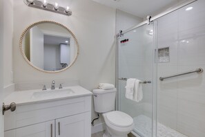 Ein Badezimmer mit Waschbecken, Spiegel, Toilette und Duschkabine aus Glas.