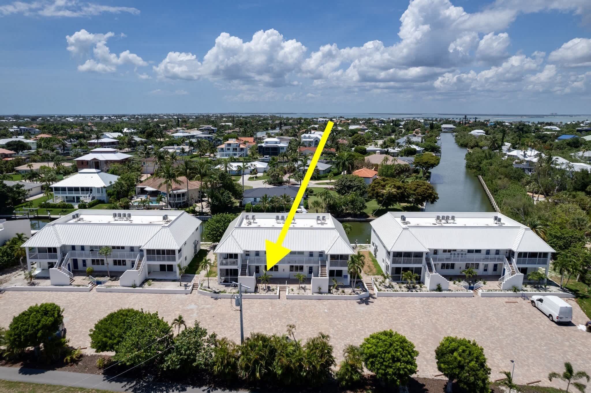 Uma área residencial com vários edifícios de dois andares, uma rua central e um corpo d'água.