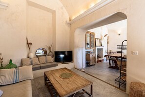 Ein Wohnzimmer mit einer Couch, Fernseher, Couchtisch und einem Essbereich mit Tisch und Stühlen.
