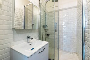 Ein Badezimmer mit einem weißen Waschbecken, einem Spiegel und einer Duschkabine.