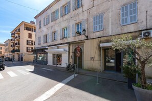 Straßenansicht mit einem Gebäude, einem Stoppschild, einer Fußgängerampel und einem abgestellten Roller.