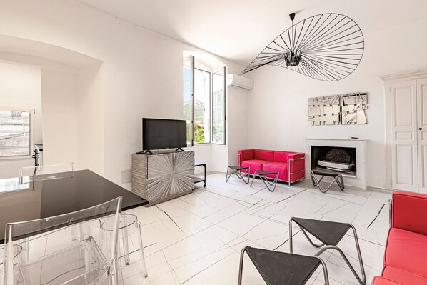 Ein modernes Wohnzimmer mit Essbereich, einem roten Sofa, einem Kamin und einem großen Fenster.