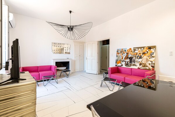 A modern living room with a fireplace, two pink sofas, a black coffee table, and a large abstract painting. - Casa Soprana - À moins d'1 km de la plage (L'Île-Rousse)