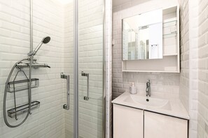 A bathroom with a glass shower enclosure, a white sink, a mirror, and a towel rack. - Casa Soprana - À moins d'1 km de la plage (L'Île-Rousse)