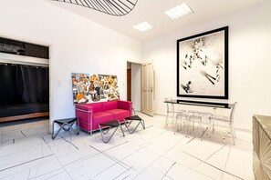 Een modern interieur met een rode bank, transparante glazen tafels en een groot, ingelijst kunstwerk aan de muur.