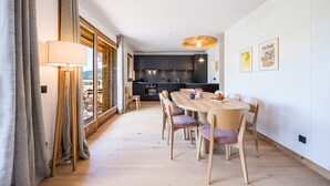Moderni keittiö, jossa on tummat kaapit, puinen ruokapöytä ja riippuvalaisin.