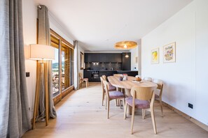 Eine moderne Küche mit dunklen Schränken, einem Holztisch und einer Pendelleuchte.