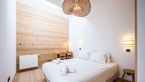 Makuuhuoneessa on puinen seinä, valkoisilla lakanoiden peitetty sänky, pieni pöytä ja riippuvalaisin.