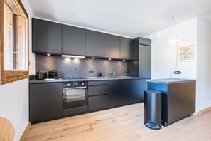 Eine moderne Küche mit dunklen Schränken, einer Marmor-Spritzschutzwand und eingebauten Geräten.
