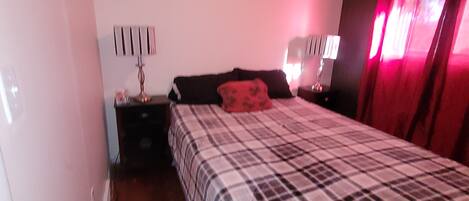 A bedroom with a bed, bedside tables, a lamp, and a ceiling light.