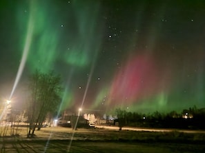 A night scene with aurora borealis, streetlights, and a building in the background.
