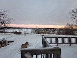 A snowy outdoor area with a wooden deck and a view of a distant town.