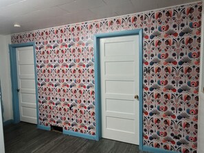A hallway with three doors, each with a blue frame and a patterned wallpaper design.
