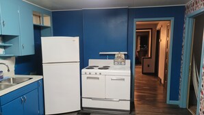 Una cocina con armarios azules, un refrigerador blanco, una estufa y un microondas.