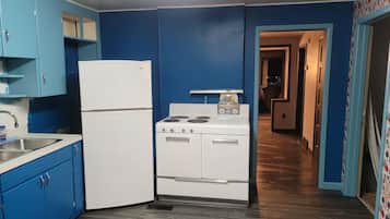 A kitchen with blue cabinets, a white refrigerator, a stove, and a microwave.
