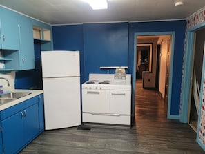 A kitchen with blue cabinets, a white refrigerator, a stove, and a microwave.