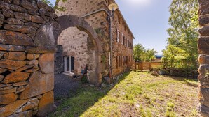 Un edificio in pietra con un portale ad arco, una recinzione in legno e un lampione.