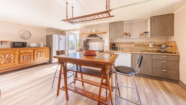 Una cucina moderna con mobili in legno, un tavolo da pranzo con una sedia e un appendiabiti a sospensione.
