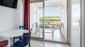 Un balcone con tavolo e sedie, una TV montata a parete e vista su un paesaggio lontano.