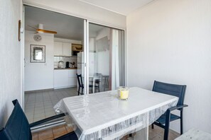 A balcony with a table, chairs, a glass door leading to a kitchen, and a ceiling fan. - Les Capitelles - Avec accès direct à la plage (Saint-Cyprien)