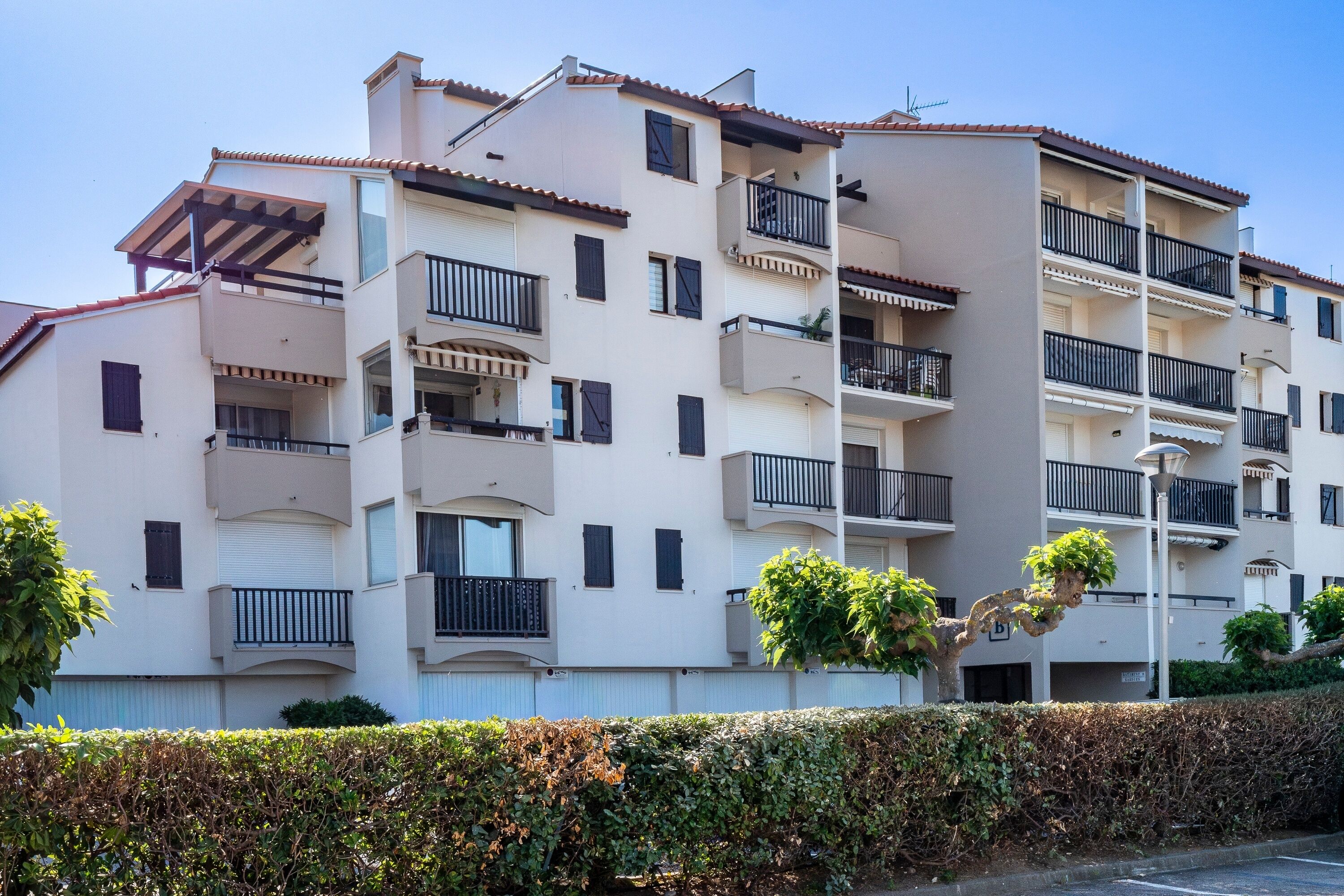 Un edificio residencial de varios pisos con balcones, techo plano y cielo despejado.