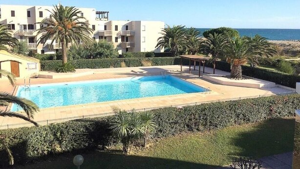 Una piscina con vista su una spiaggia e un edificio con balconi.