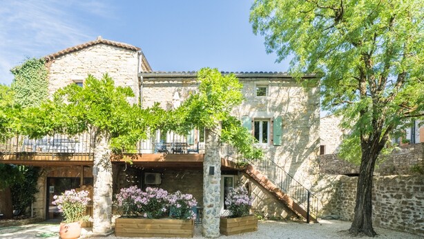 A stone building with a balcony, a gravel courtyard, and flowering plants. - Les Magnans - Grospierres (Grospierres)