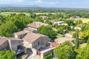 A rural village with stone buildings, a swimming pool, and surrounding greenery. - Le Cocon - Grospierres (Grospierres)