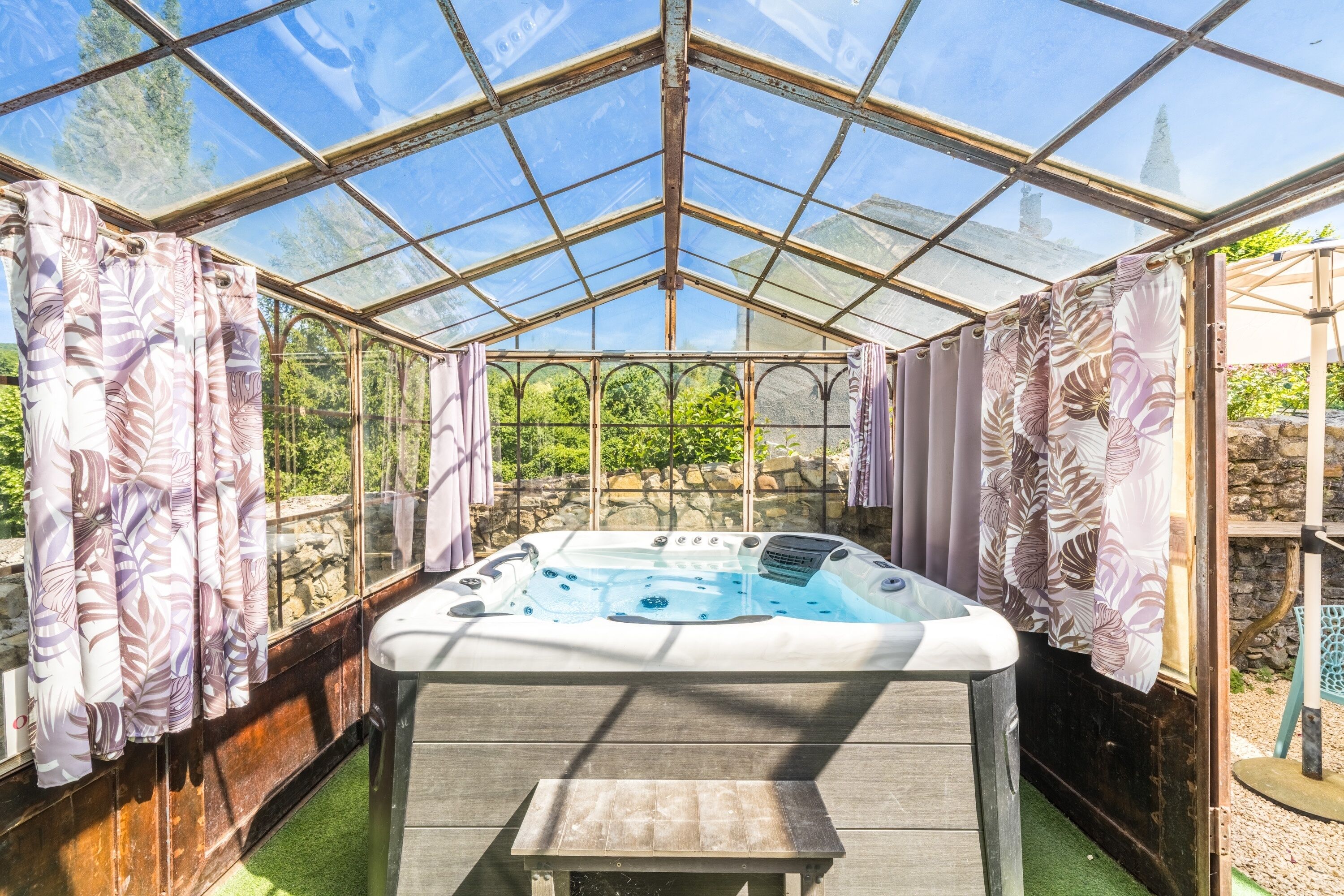 Une serre équipée d’un jacuzzi, d’un plancher en bois et de rideaux.