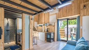 A wooden interior with a kitchen, a shower, and a sofa. - Le Cocon - Grospierres (Grospierres)