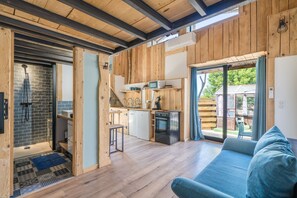 A wooden interior with a kitchen, a shower, and a sofa. - Le Cocon - Grospierres (Grospierres)