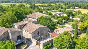 A rural village with stone buildings, a swimming pool, and surrounding greenery. - Le Studio - Grospierres (Grospierres)