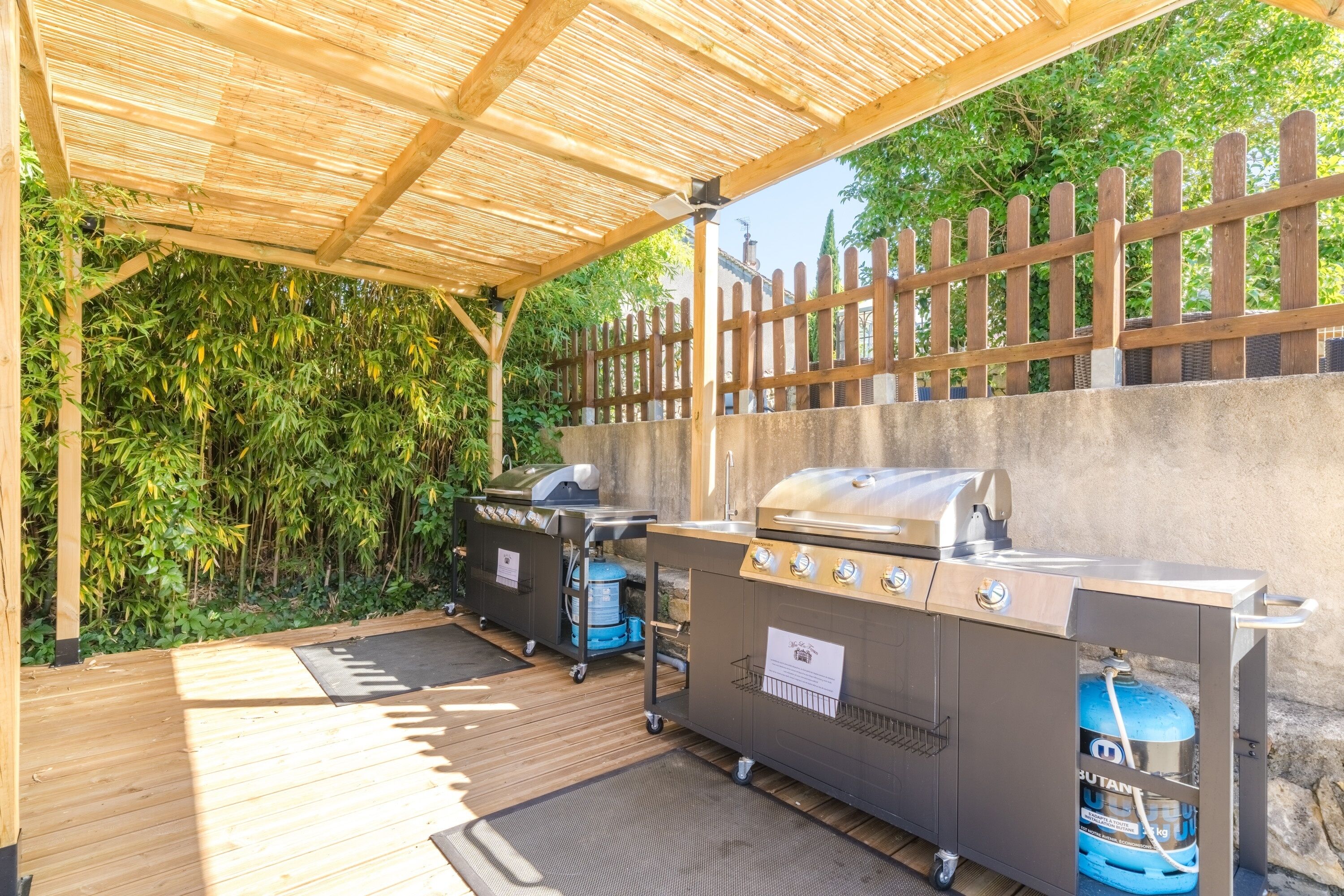 Un espace barbecue extérieur équipé d’un gril, d’une bouteille de gaz et d’une glacière portative.