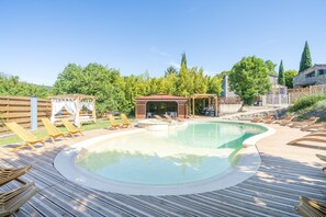 En swimmingpool med solstolar, en pergola och ett trädäck.