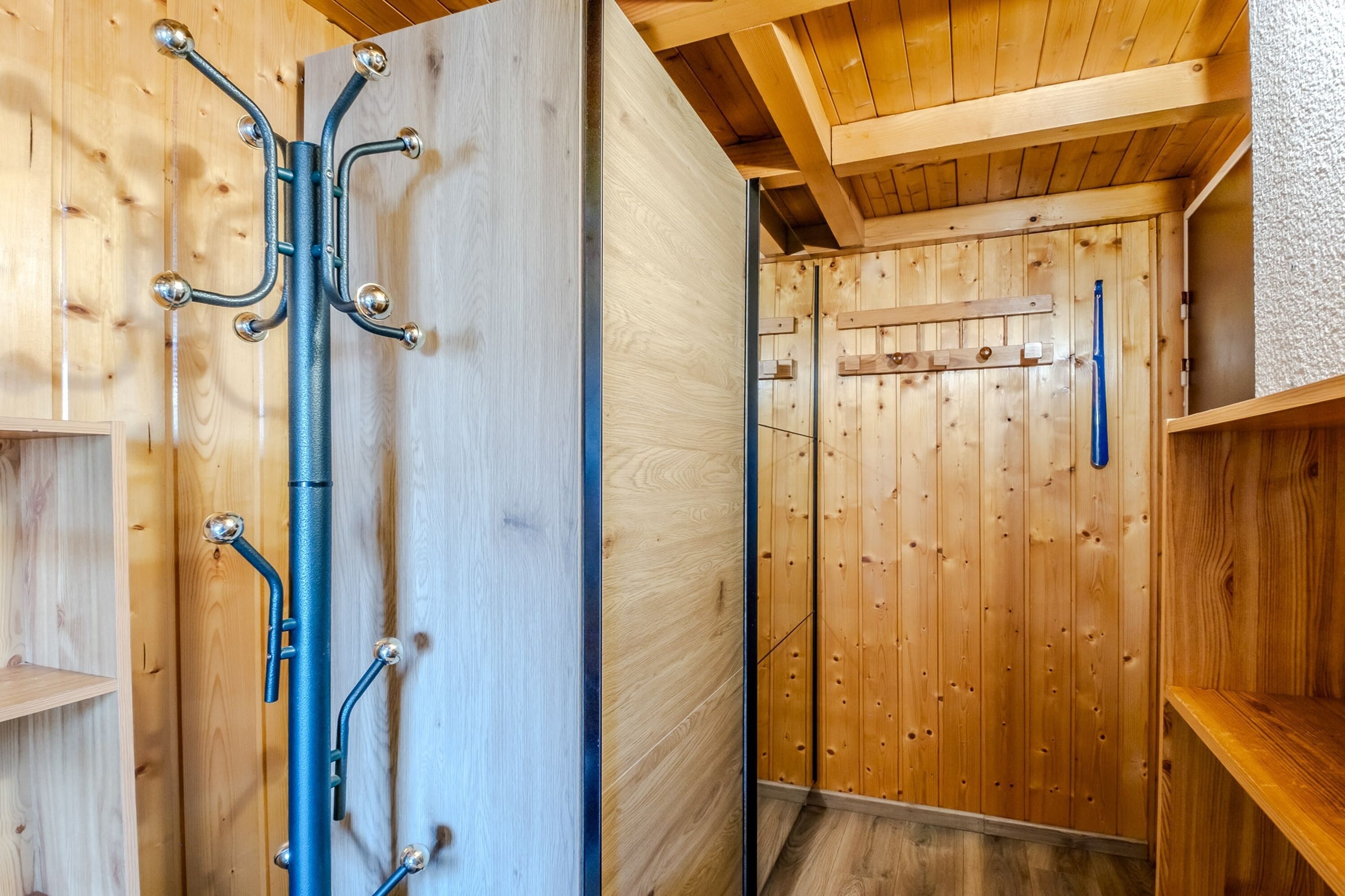 A wooden interior with a metal rack with hooks, wooden walls, and a wooden ceiling.