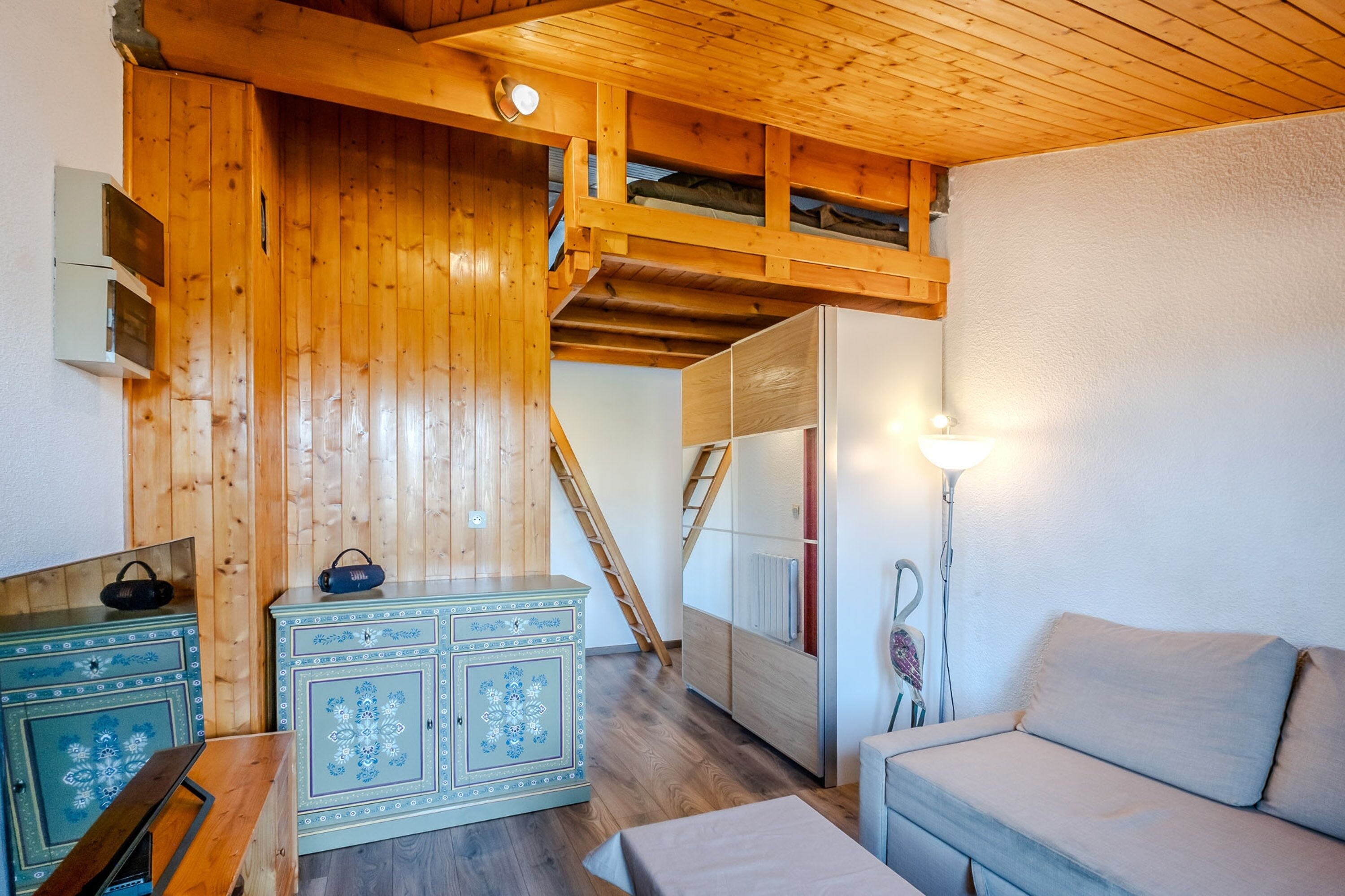 Ein Holzinnenraum mit einer Couch, einem Schrank und einer Treppe.