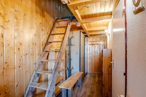 Ein Holzinnenraum mit einer Holztreppe, einer Bank und einer Tür mit der Aufschrift 'Chambre'.