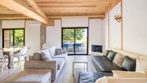 Ein modernes Wohnzimmer mit Holzboden, einer Sofagarnitur, einem Fernseher und einem Essbereich mit Stühlen und einem Tisch.