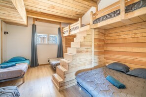Una cabaña de madera con literas, una escalera y un ventanal.
