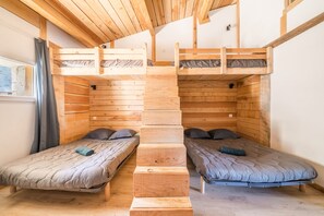 Een kamer met twee stapelbedden, houten wanden en een raam met gordijnen.