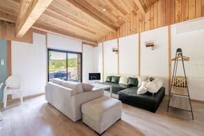 Ein modernes Wohnzimmer mit einer Couch, Hocker, Fernseher und Holzboden.