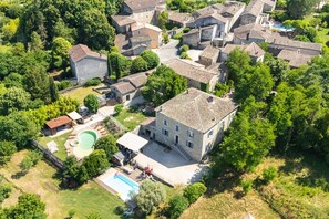 Luchtbeeld van een woongebied met stenen gebouwen, een zwembad en een groot huis met een schuin dak.