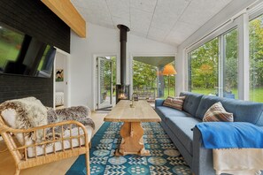A modern living room with a sofa, a wooden coffee table, and a fireplace. - Holiday home with large doors and forest (Gilleleje)