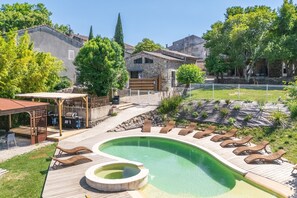 A swimming pool with lounge chairs, a pergola, and a stone building in the background. - Le Mas - Grospierres (Grospierres)