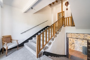 A staircase with wooden railings, a chair, and a stone wall with a fireplace. - Le Mas - Grospierres (Grospierres)